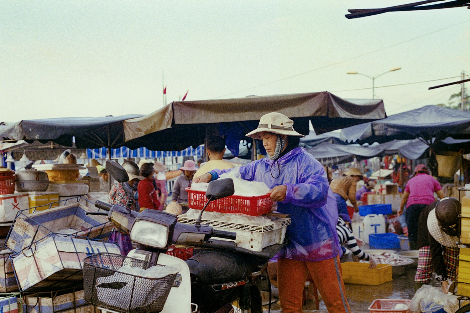35mm photo of a woman preparing fish for transport on her scooter, vietnam